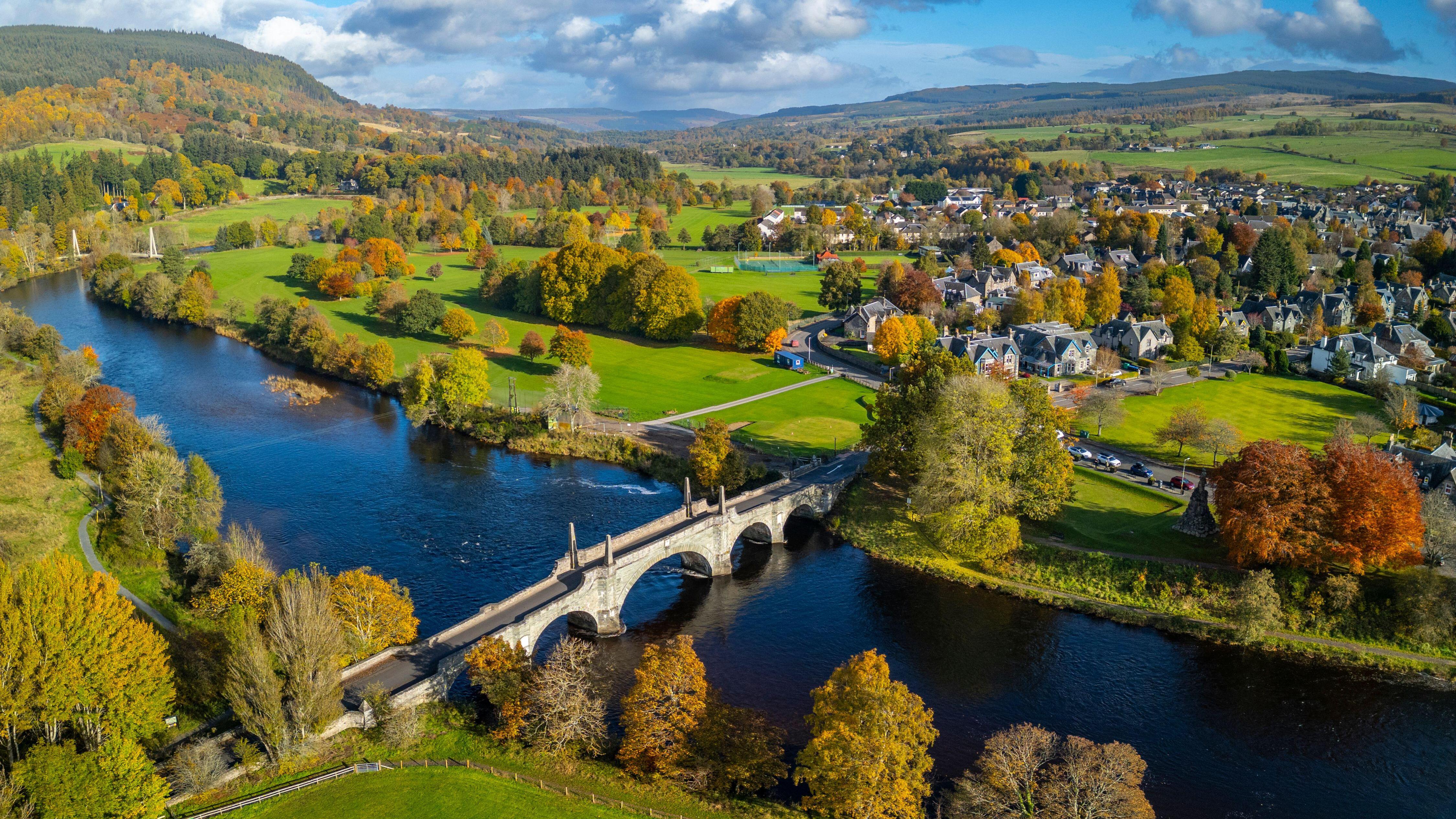 Cittadina delle Highlands scozzesi con fiume, ponti e colline sullo sfondo